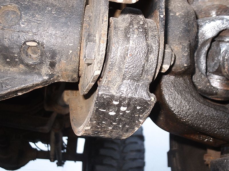 Underside close-up of a greasy cast-iron differential and axle housing with bolts
