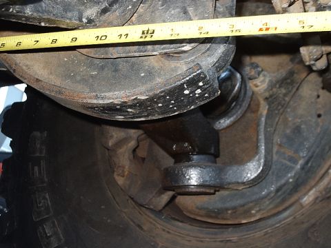 1996 Ford Bronco - A tape measure is used to measure a suspension part on a vehicle.