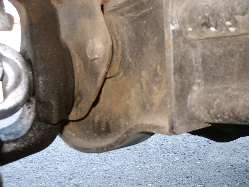 Dirty underside cast metal axle or differential housing over concrete