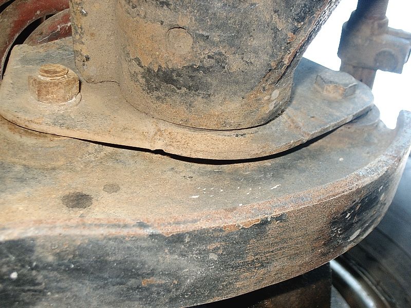 Rusty undercarriage bracket with hex bolts and heavy surface corrosion