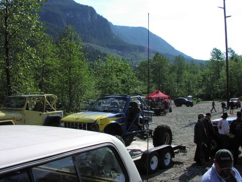 1993 Ford Bronco - An off-road buggy with a blue and yellow paint scheme is loaded onto a trailer at an outdoor event.