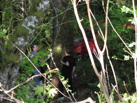 1993 Ford Bronco - A red 1993 Ford Bronco is partially visible in a wooded area, with two individuals nearby.