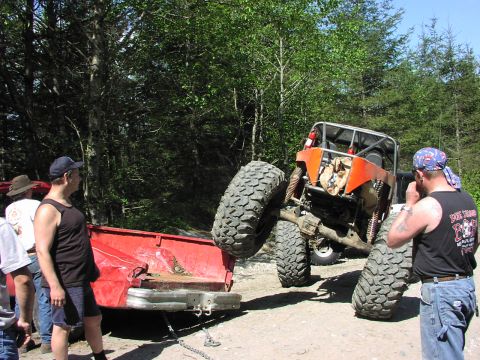 1993 Ford Bronco - An off-road buggy is being pulled out of a ditch by a red pickup truck in a wooded area.