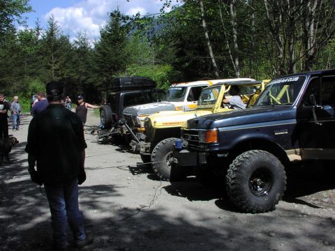 1993 Ford Bronco - Several off-road vehicles, including a 1993 Ford Bronco, are parked together on a dirt road.