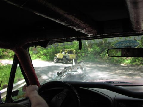 1993 Ford Bronco - An overturned vehicle lies on a dirt road, with a yellow Jeep visible in the background.