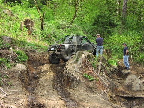1993 Ford Bronco - Off-road vehicle navigates a challenging muddy terrain with onlookers present.
