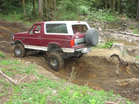 1993 Ford Bronco - This Ford Bronco is navigating a challenging off-road course with steep inclines and muddy terrain.