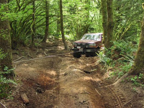 1993 Ford Bronco - Ford Bronco navigating a challenging off-road path in a wooded area.