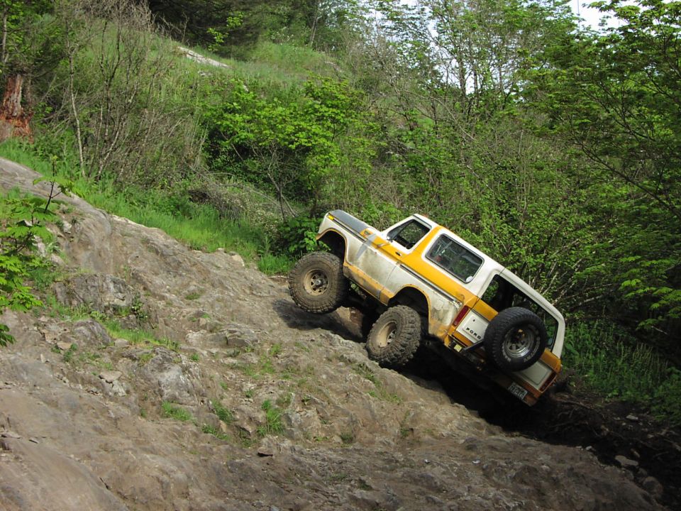 Yellow and white off-road SUV climbing a rocky hill. Visible text: SUPERMOTORS