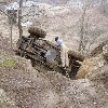 1992 Ford Bronco - A vehicle has overturned on a muddy incline, with a person still inside the cabin.