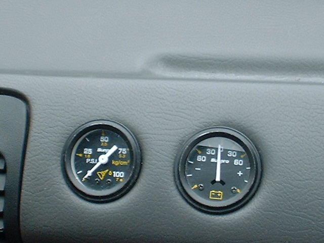 Aftermarket oil pressure and ammeter gauges mounted in a gray dashboard