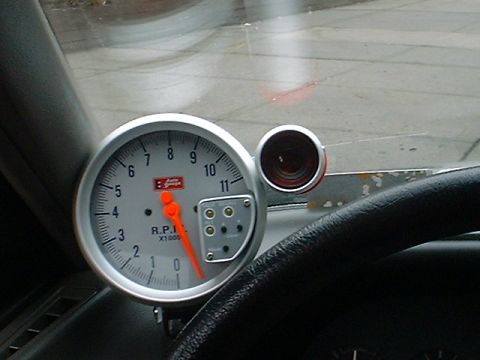 1991 Ford Escort - Aftermarket tachometer and gauge cluster installed in a vehicle interior.