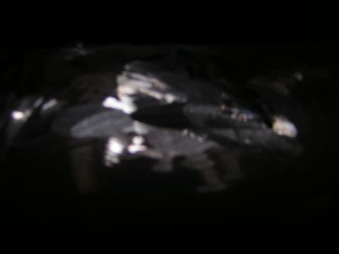 1995 Ford Bronco - A very dark, blurred nighttime photo showing only scattered glare reflections off what appears to be a dark painted surface; the subject ca…