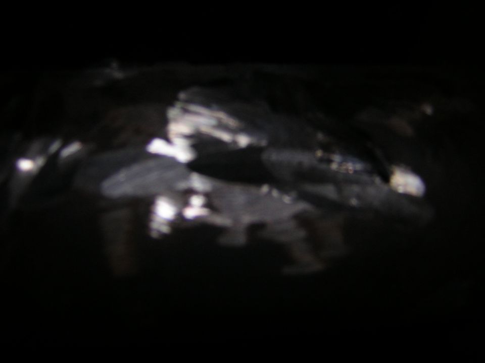 Very dark blurred night photo with only glare reflections; subject not identifiable