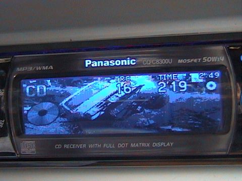 1991 Ford Bronco - Close-up of a Panasonic CQ-C8300U MP3/WMA car CD receiver's blue dot-matrix display, showing CD track 16 at 2:19 elapsed over a custom truc…