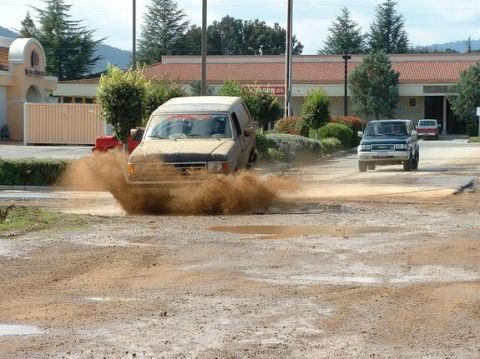 1991 Ford Bronco - A mud-covered Ford Bronco blasting head-on through a large muddy puddle in a shopping-center parking lot, throwing a wide brown spray from…