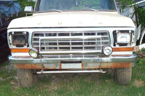 1979 Ford Bronco - This truck's front end shows a large chrome grille and a heavily rusted bumper with auxiliary lights.