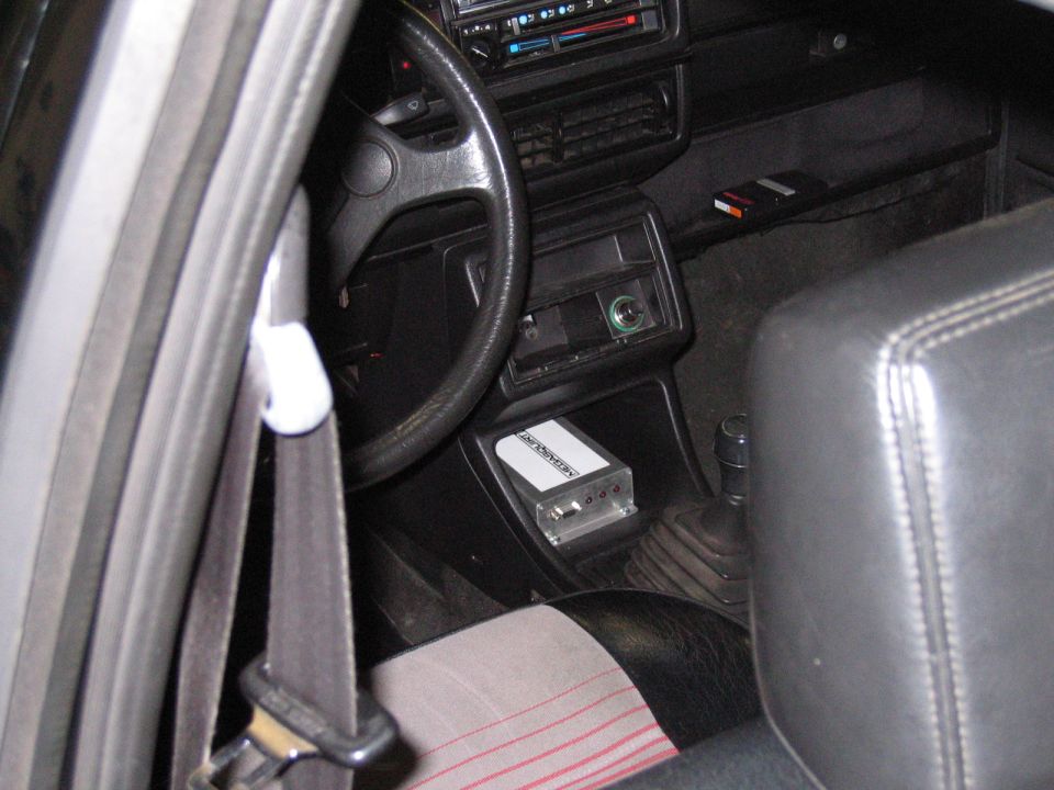 Car interior showing steering wheel, dashboard, gear shifter, and an aftermarket amplifier