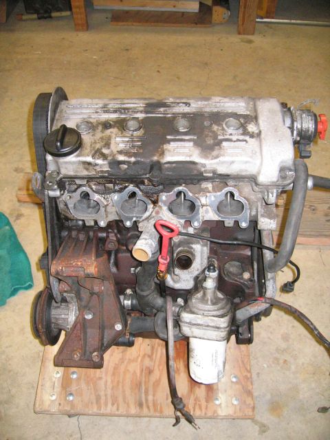 1987 Volkswagen Golf - Engine assembly with visible oil filter and belt pulley, mounted on a wooden base.