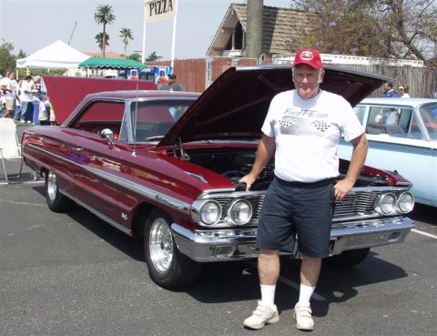 1964 Ford Galaxie - A man poses with his red 1964 Ford Galaxie at an outdoor car show.
