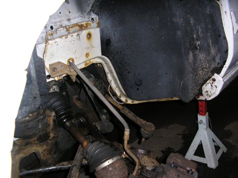 1998 Ford Taurus - Close-up of corroded vehicle suspension parts and a jack stand.