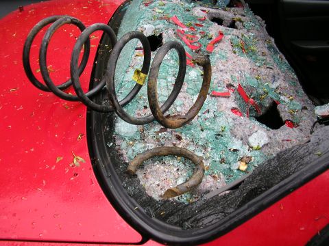 1998 Ford Taurus - Broken windshield and loose springs are visible on the hood of a red vehicle.