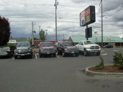 1994 Ford Explorer - Several pickup trucks are parked in a lot outside a Hooters restaurant.