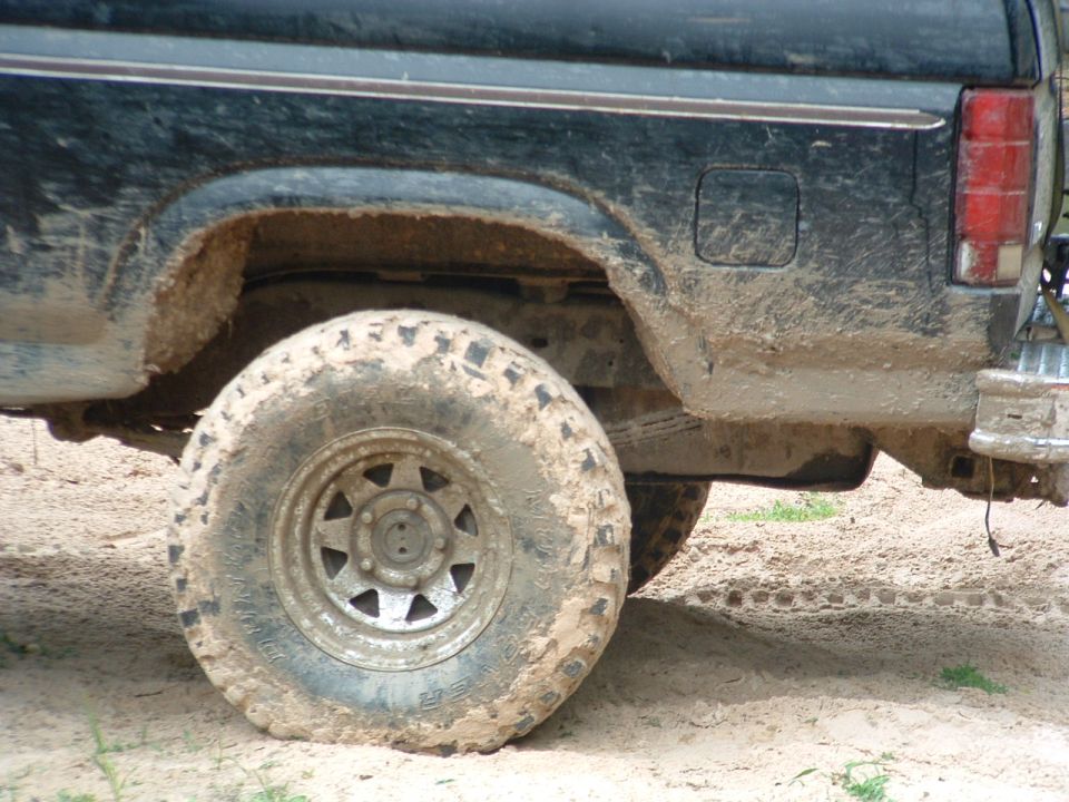 Mud-covered black 1980s Ford Bronco rear quarter panel and tire