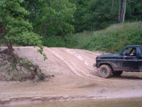 1993 Ford Bronco - This black SUV appears to be from the early 1980s, possibly a Ford Bronco, navigating a sandy incline.