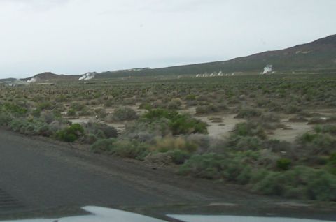 1994 Ford F-150 - Steam plumes rise from geothermal activity in a wide, dry terrain under an overcast sky.