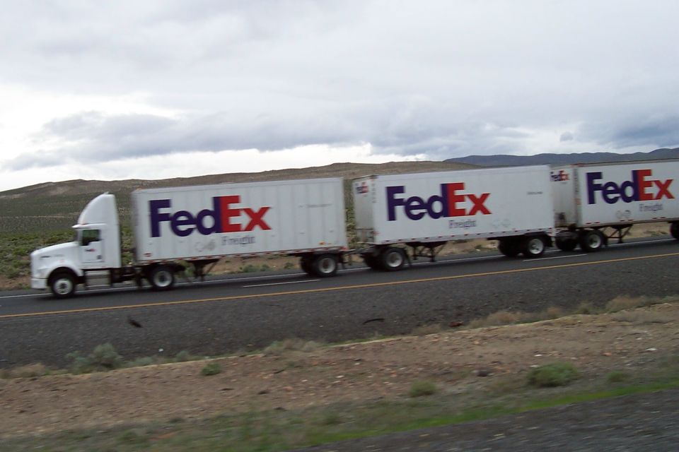 White FedEx semi-truck with two white trailers driving on a highway