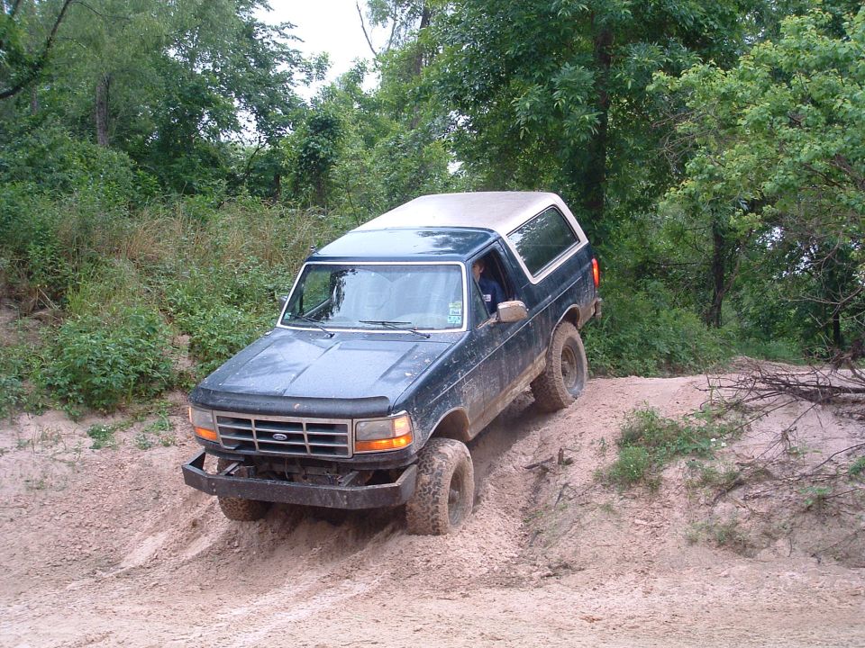 Dark blue 1993 Ford Bronco climbing a dirt hill