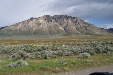 1994 Ford F-150 - A vast mountain range dominates the horizon under a dramatic, cloudy sky, with sagebrush covering the foreground.
