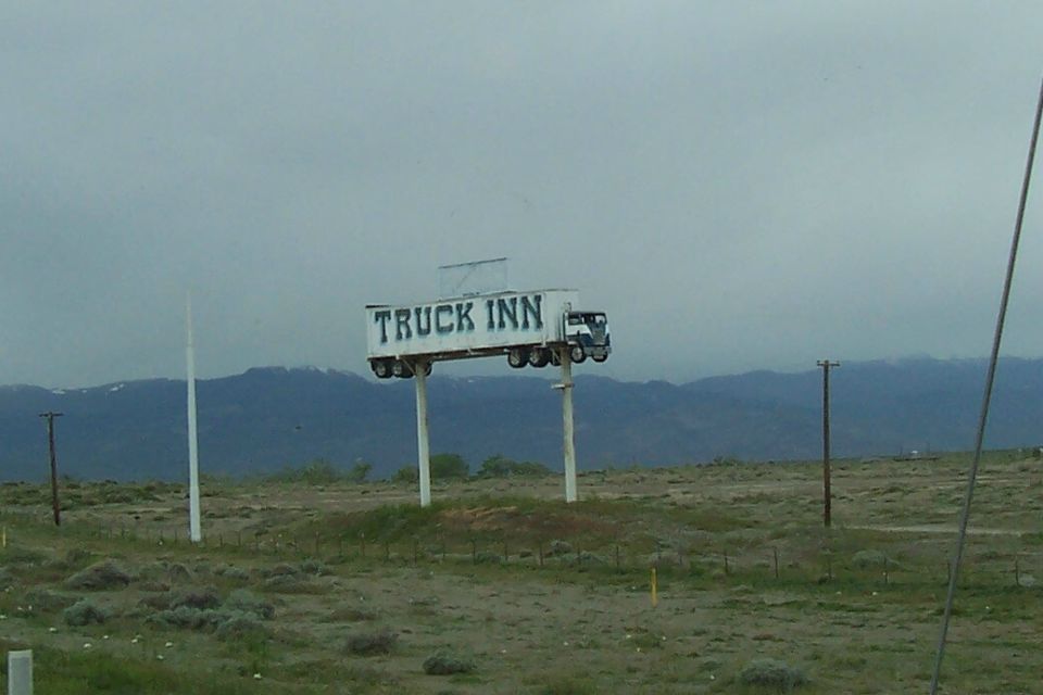 billboard with 'TRUCK INN' written on it, shaped like a semi-truck, on two poles
