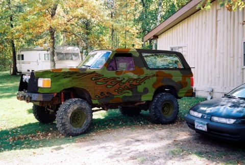1993 Ford Bronco - This 1993 Ford Bronco features a unique camouflage paint scheme with flame decals and lifted suspension.