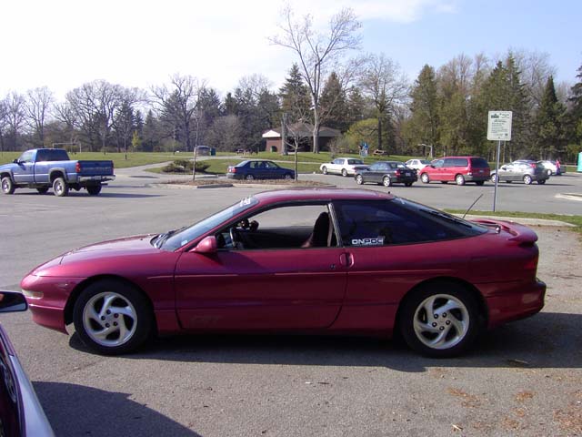 1989 Ford Probe coupe parked in a lot with a blue pickup truck in the background