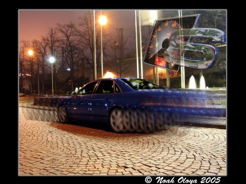 1995 Ford Probe - A blue sedan is captured in motion blur on a cobblestone street at night, with a superimposed speedometer graphic.