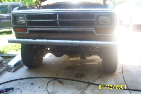 1979 Ford F-150 - The front grille and bumper of a 1979 Ford F-150 are visible, with the hood open and another vehicle in the background.