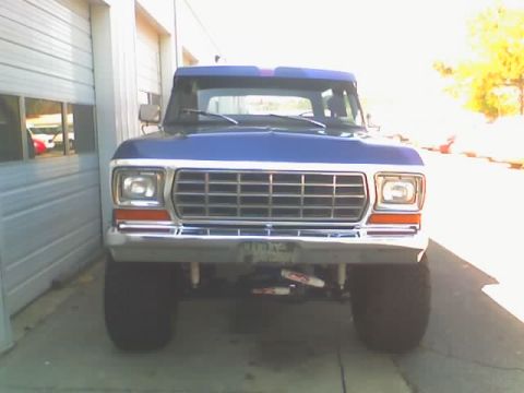 1979 Ford F-150 - This 1979 Ford F-150 pickup truck is shown from the front, parked outside a garage with a bright yellow tree in the background.