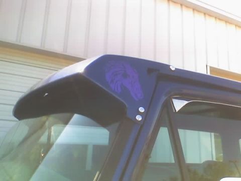 1979 Ford F-150 - A dark blue pickup truck features a purple dragon decal on its roof visor.