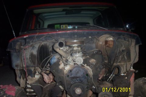 1979 Ford F-150 - The engine bay of a red truck is shown with the hood removed, revealing the engine and surrounding components.
