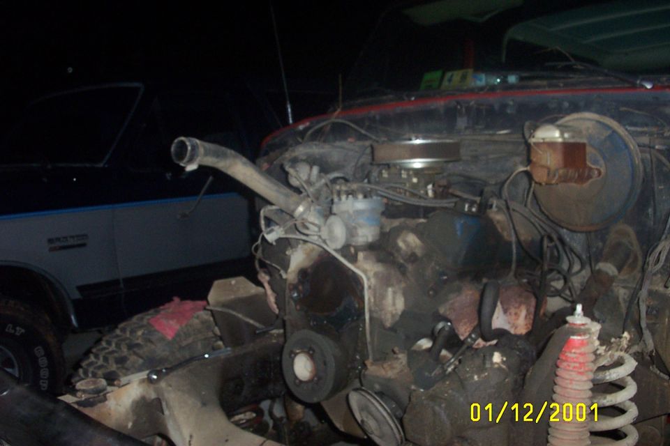 1979 Ford F-150 engine bay with visible V8 engine components and a portion of another truck in the background