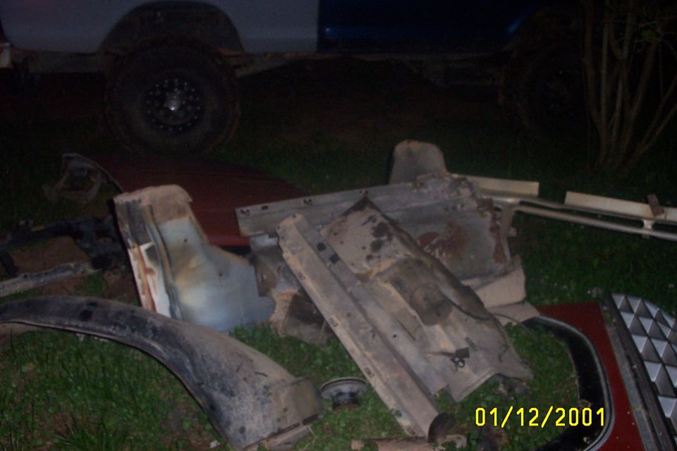 Scattered vehicle parts including a fender and grille, with a date stamp of 01/12/2001
