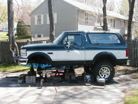 1994 Ford Bronco - This 1994 Ford Bronco is elevated on jack stands for maintenance, revealing its underside and off-road tires.