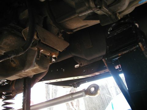 1994 Ford Bronco - A view of the underside of a vehicle, showing mechanical parts and suspension, raised on jacks.