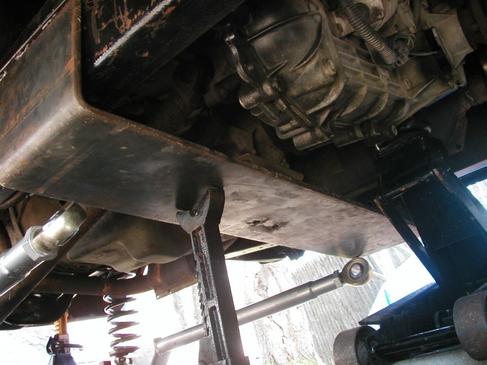 Vehicle underbody with skid plate and transmission visible, supported by jack stands