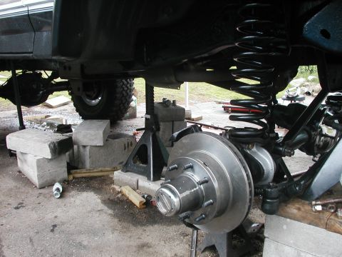 1994 Ford Bronco - Undercarriage of a vehicle undergoing brake repair, showing suspension and axle components.