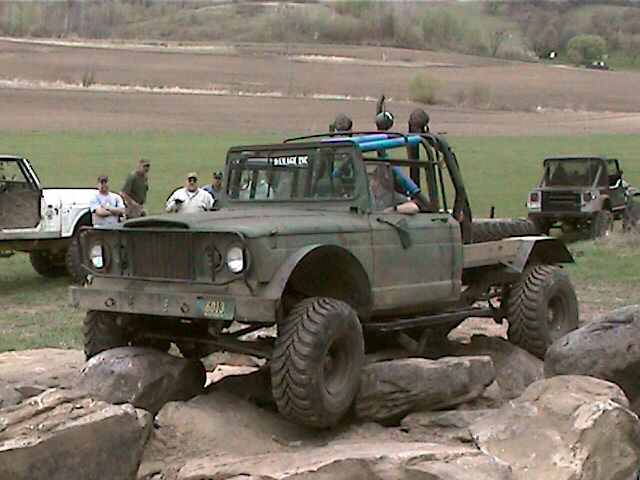 Olive green off-road truck with roll cage navigating rocks