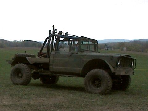 1977 Ford F-150 - Modified military truck with roll cage and off-road tires sits in a grassy field.