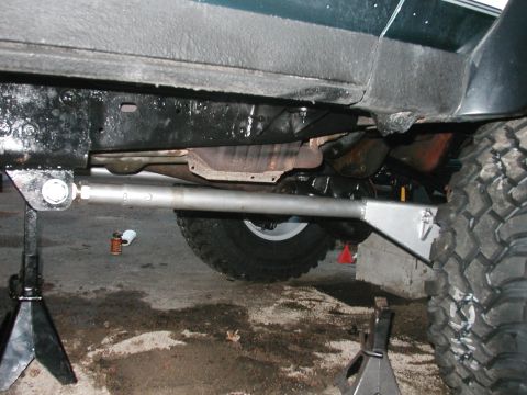1994 Ford Bronco - Underside view of a green vehicle with modified suspension components and large off-road tires, supported by jack stands.